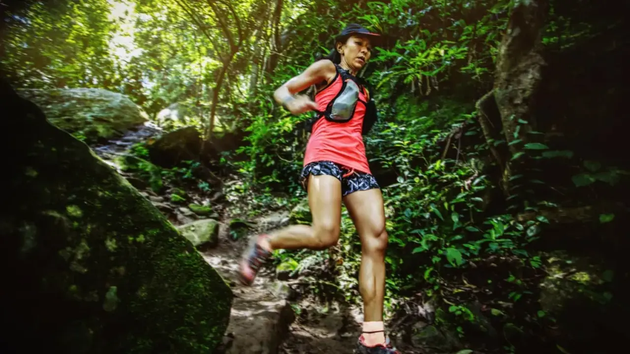 Läuferin bewältigt eine anspruchsvolle ultramarathon distanz auf einem schmalen, steinigen Pfad im dichten Dschungel.