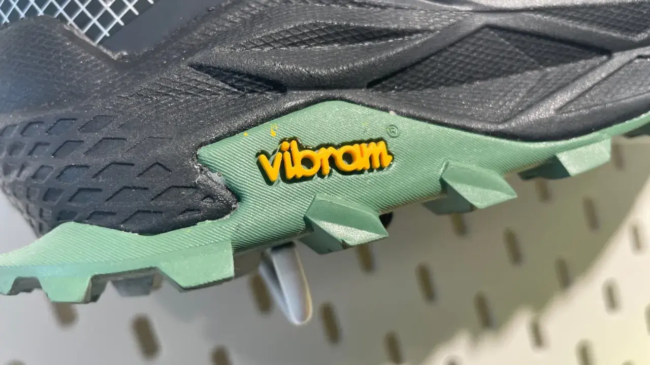 Detailaufnahme einer grünen Vibram Sohle mit gelbem Logo. Mögliche Nachteile: Abnutzung des Profils bei starker Beanspruchung.