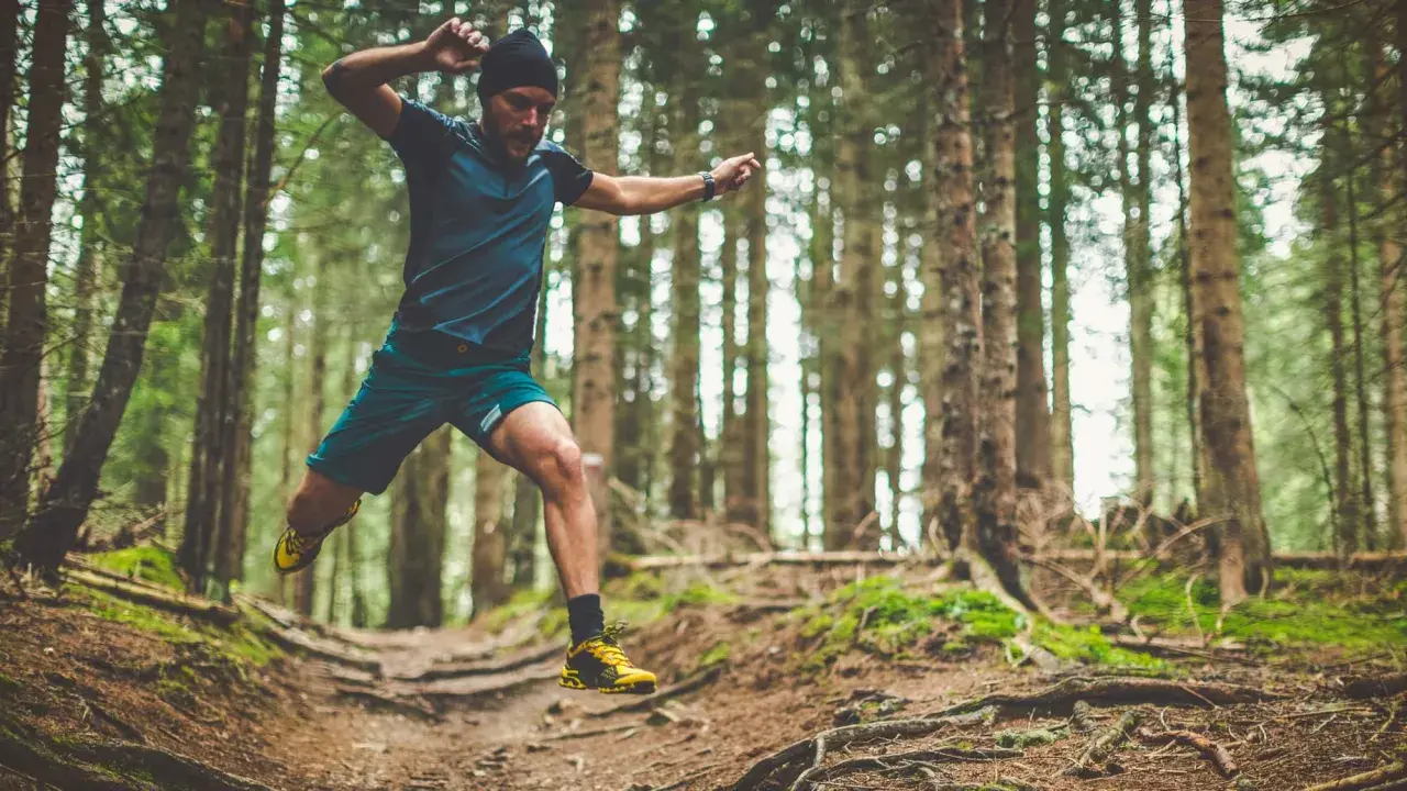 Mann im Sprung beim trailrunning training im Wald.