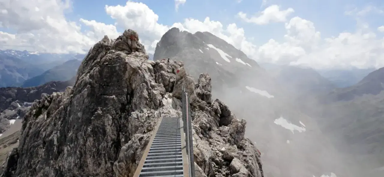Ein steiler Metallsteg führt über felsige Gipfel. Ein Abenteuer auf dem Heilbronner Weg wandern.