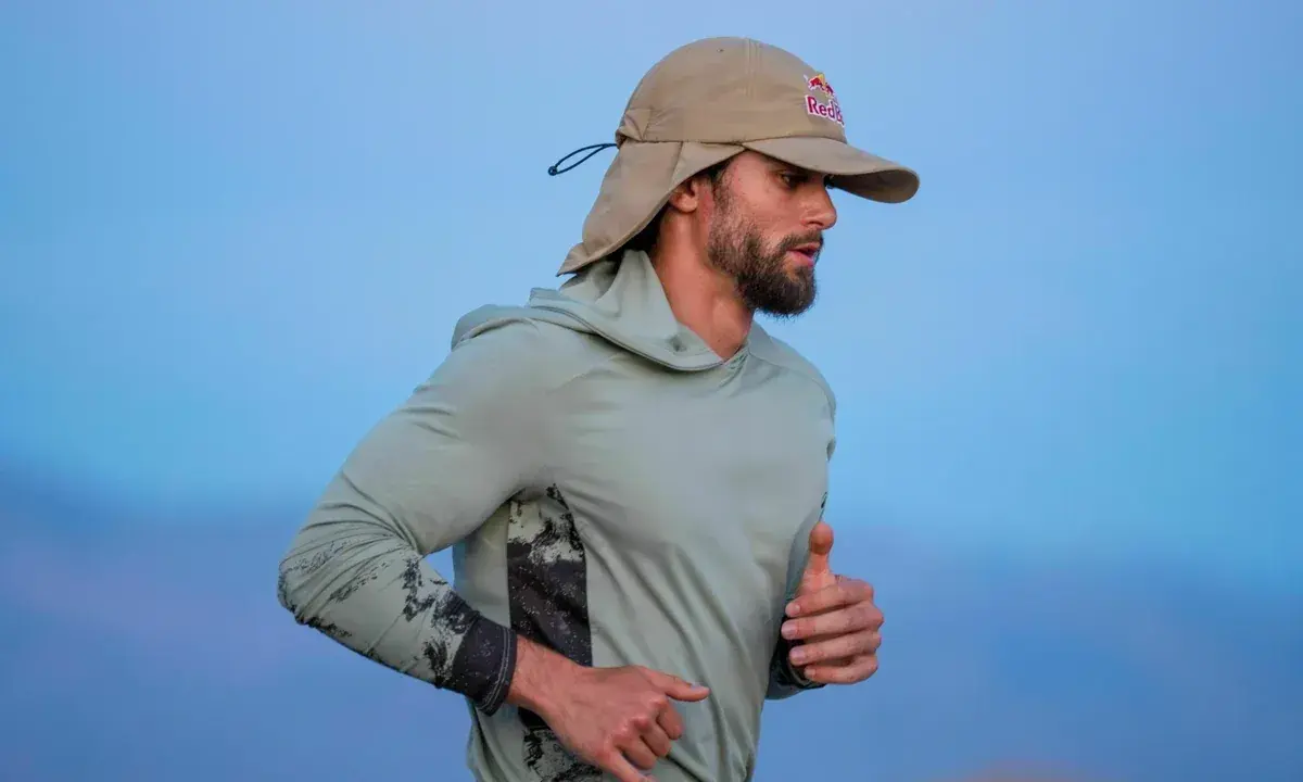 Läufer mit Bart und Sonnenschutz-Cap von Red Bull im Laufschritt, auf dem Weg zum Ultramarathon Weltrekord.