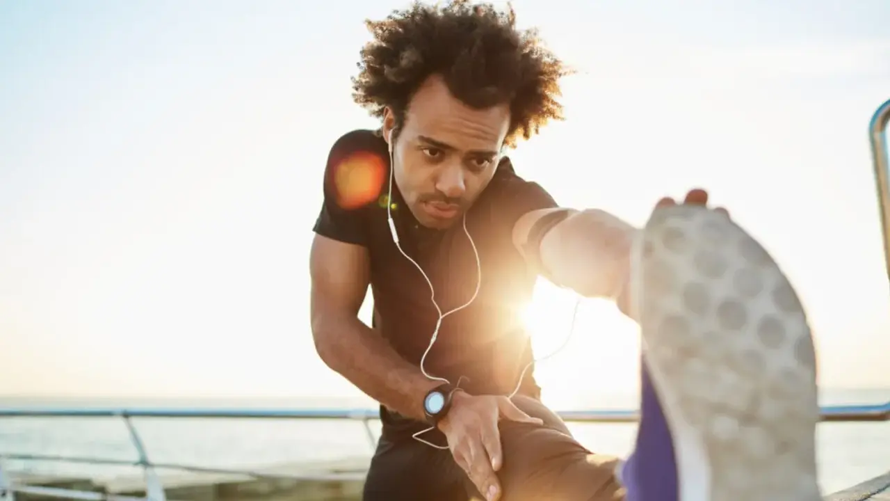 Mann dehnt sich am Meer, wichtig für die Regeneration nach Halbmarathon.