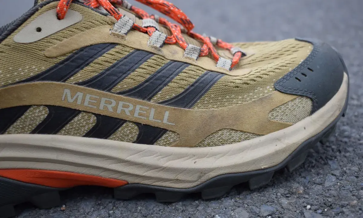 Detailaufnahme eines Merrell Wanderschuhs im Test. Der Schuh ist in Beige- und Brauntönen gehalten, mit orangefarbenen Schnürsenkeln und schwarzen Akzenten.