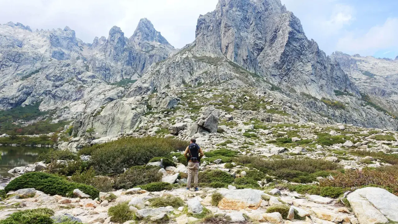 Wanderer in Korsika im August, genießt die kühlen Bergtage. Die majestätischen Gipfel und die raue Landschaft laden zum Erkunden ein.