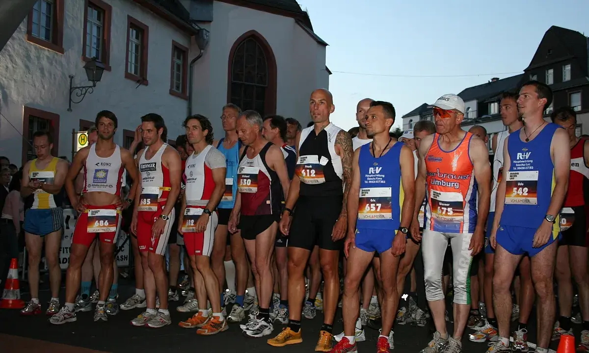 Läufer warten am Start des Sommernachtslauf Limburg. Sie tragen Laufbekleidung und Startnummern.