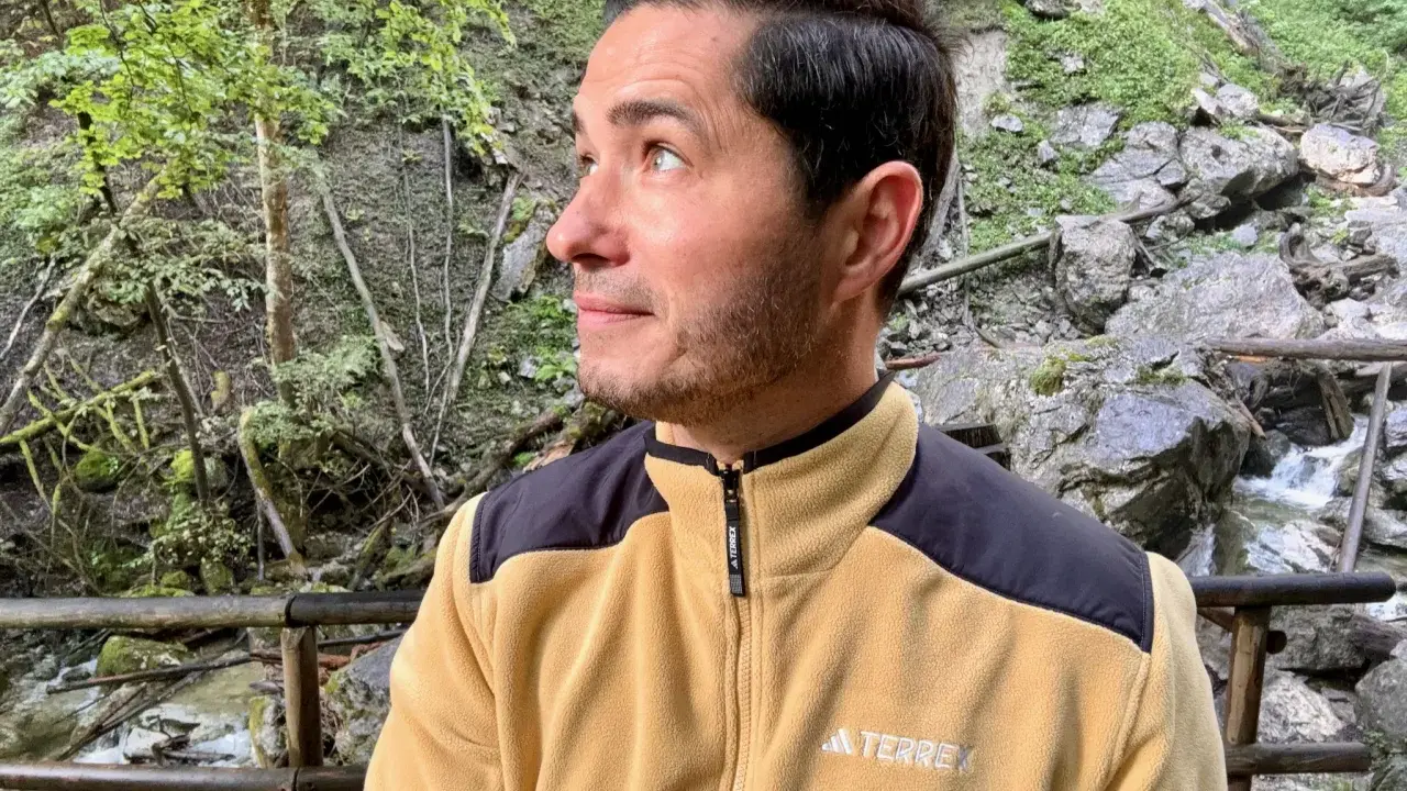 Mann in gelber Fleecejacke mit schwarzem Kragen und Schulterpartien, die zeigt, welche Fleecejacke wirklich warm ist.