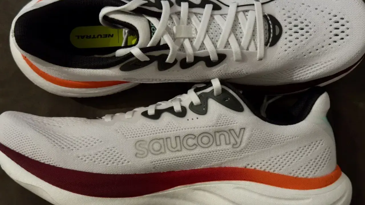 Zwei weiße Laufschuhe, die Saucony Ride 19, mit roten und orangen Akzenten. Perfekt für neutrale Läufer.