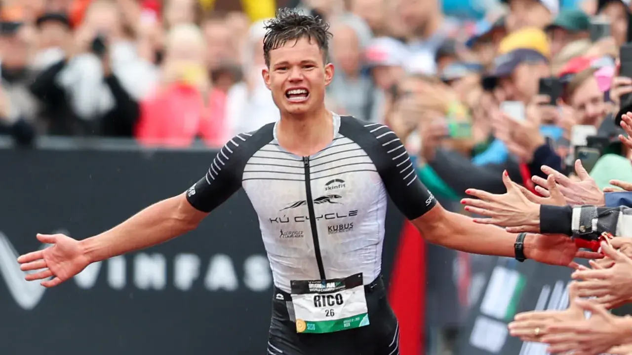 Triathlet Rico feiert seinen Zieleinlauf beim Ironman Luxembourg. Jubelnde Zuschauer reichen ihm die Hände.