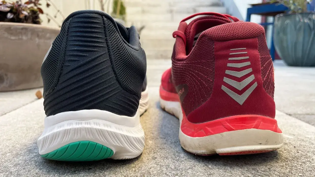 Zwei Laufschuhe, ein schwarzer und ein roter, stehen nebeneinander. Der rote Schuh trägt das Logo "altra rivera".