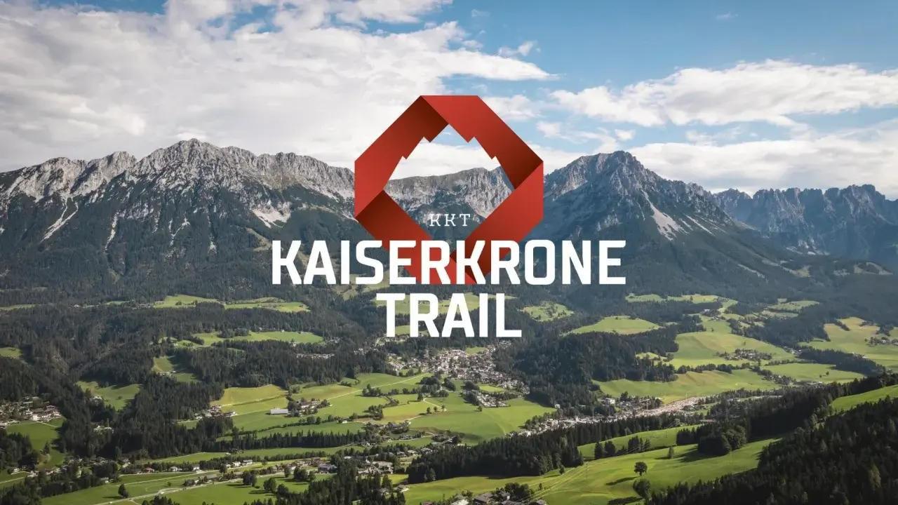 Majestätische Berge über grünen Tälern, mit dem Schriftzug "KAISERKRONE TRAIL" und einem roten Logo.