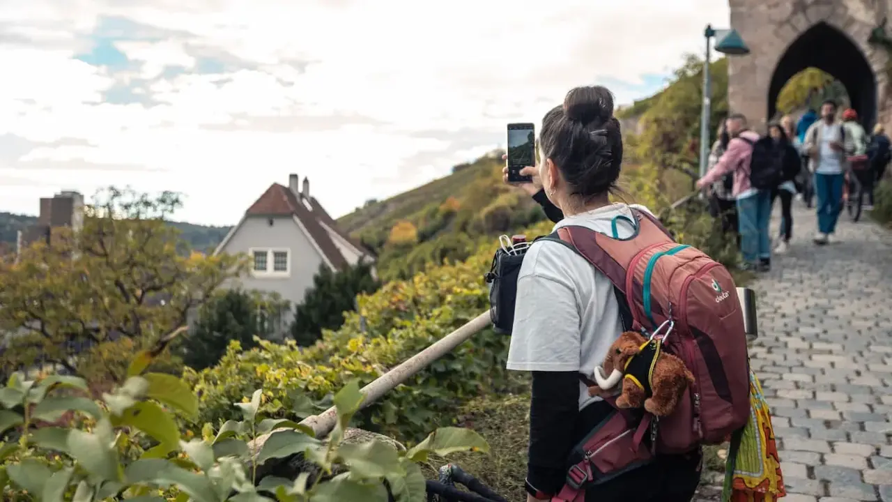 Frau macht Foto auf Wanderung bei Stuttgart. Weinberge und Häuser im Hintergrund.