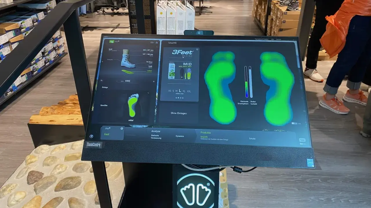 Bildschirm zeigt eine Laufschuh Analyse mit Fußabdrücken und Druckpunkten. Die Software "Smartfit" hilft bei der Auswahl des passenden Schuhs.