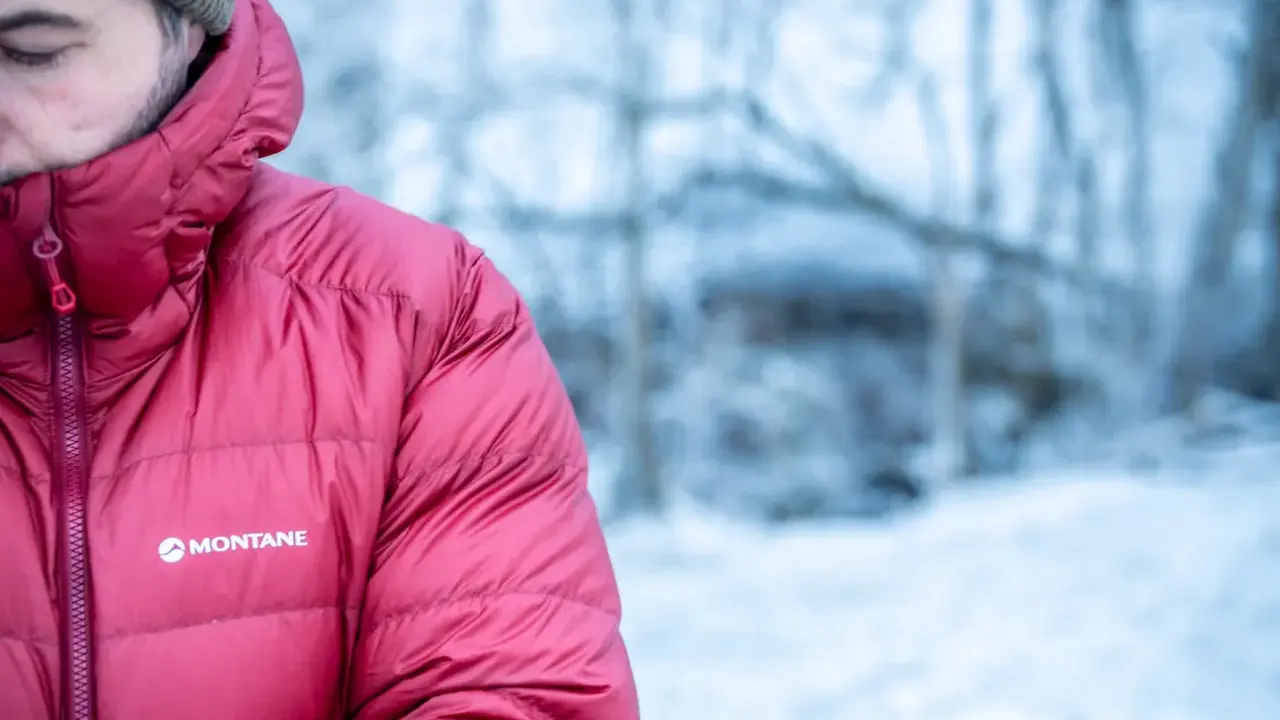 Mann in roter Montane-Jacke mit Kapuze im Schnee. Gute thermore ecodown erfahrungen im Winter.