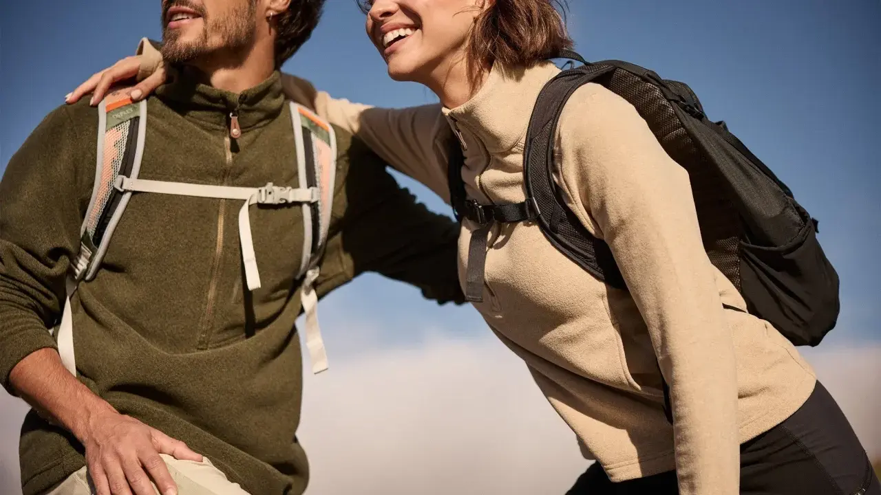 Glückliches Paar in warmen Fleece-Pullovern und Rucksäcken genießt die Natur. Fleece ist weich und isolierend.