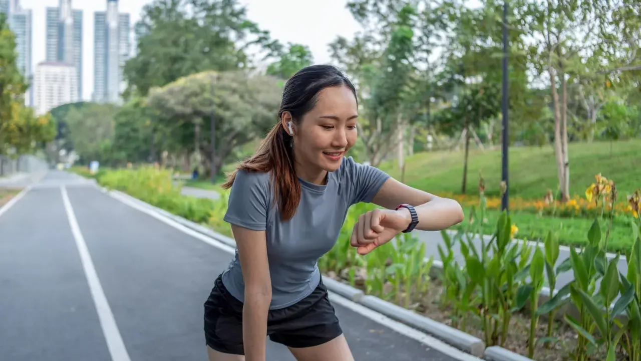 Läuferin prüft ihren Puls beim Joggen. Ihr Herz schlägt bei 180 Schlägen pro Minute. Sie ist eine Frau, die fit ist.