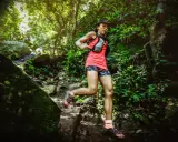 Läuferin bewältigt eine anspruchsvolle ultramarathon distanz auf einem schmalen, steinigen Pfad im dichten Dschungel.