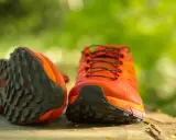 Leuchtend orange Trailrunning-Schuhe mit grobstolliger Sohle, bereit für neue Abenteuer. Perfekt, um bergschuhe neu besohlen zu lassen und wieder loszulegen.