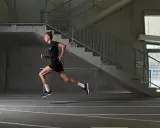 Läufer im Sprung, konzentriert auf sein stabi training. Beton, Stahl und eine Laufbahn bilden die Kulisse für seine dynamische Bewegung.