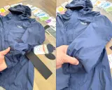 Blaue Regenjacke reparieren: Ein Loch im Ärmel wird mit einem Reparaturflicken aus dem Set ausgebessert.