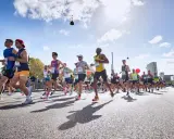 Läufer in einem Marathon, die ihr Lungenvolumen trainieren. Die Sonne scheint, der Himmel ist blau mit Wolken.
