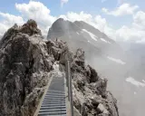 Ein steiler Metallsteg führt über felsige Gipfel. Ein Abenteuer auf dem Heilbronner Weg wandern.