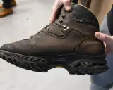 Brauner, abgenutzter Wanderschuh wird gehalten. Die Sohle ist stark abgenutzt, was zeigt, dass die Schuhe besohlen lassen werden müssen, um sie wieder einsatzfähig zu machen.