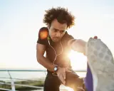 Mann dehnt sich am Meer, wichtig für die Regeneration nach Halbmarathon.