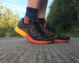 Asics Gel NoosaFast Laufschuhe in Schwarz mit orangen Akzenten, bereit für den nächsten Lauf im Grünen.