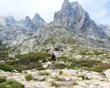 Wanderer in Korsika im August, genießt die kühlen Bergtage. Die majestätischen Gipfel und die raue Landschaft laden zum Erkunden ein.