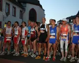 Läufer warten am Start des Sommernachtslauf Limburg. Sie tragen Laufbekleidung und Startnummern.
