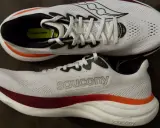 Zwei weiße Laufschuhe, die Saucony Ride 19, mit roten und orangen Akzenten. Perfekt für neutrale Läufer.
