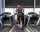 Mann mit Kopfhörern absolviert ein intensives Laufband Training im Fitnessstudio.