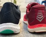 Zwei Laufschuhe, ein schwarzer und ein roter, stehen nebeneinander. Der rote Schuh trägt das Logo "altra rivera".