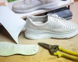 Schuhe mit Abrollsohle im Test: Ein Muster, eine Sohle und eine Schere liegen bereit.