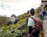 Frau macht Foto auf Wanderung bei Stuttgart. Weinberge und Häuser im Hintergrund.