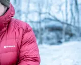 Mann in roter Montane-Jacke mit Kapuze im Schnee. Gute thermore ecodown erfahrungen im Winter.