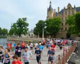 Teilnehmer des 5 Seen Lauf Schwerin überqueren eine Brücke vor dem Schloss.