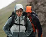 Zwei Wanderer im Regen. Die Frau trägt eine hellblaue Jacke, die perfekt ist, wenn man sich fragt, welche Jacke zum Wandern bei schlechtem Wetter am besten geeignet ist.