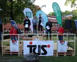 Siegerehrung beim Hachelauf Syke: Läufer auf dem Podium, Moderation und Sponsoren-Banner im Hintergrund.