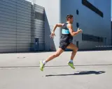 Ein Mann in Sportkleidung läuft mit hoher Kadenz vor einer modernen Industriehalle.