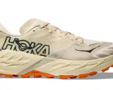 Beiger Hoka Speedgoat 7 Trailrunningschuh mit orangefarbener Vibram-Sohle und dunklem Hoka-Logo.