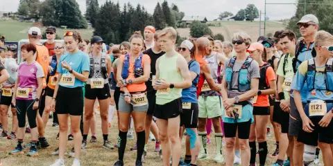 Läufer stehen bereit für den Lauf "3 Kings 3 Hills". Die Teilnehmenden tragen Startnummern und Laufbekleidung.