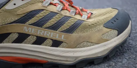 Detailaufnahme eines Merrell Wanderschuhs im Test. Der Schuh ist in Beige- und Brauntönen gehalten, mit orangefarbenen Schnürsenkeln und schwarzen Akzenten.