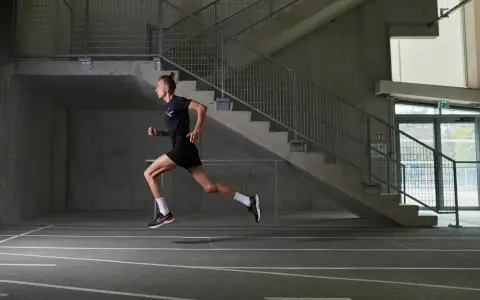 Läufer im Sprung, konzentriert auf sein stabi training. Beton, Stahl und eine Laufbahn bilden die Kulisse für seine dynamische Bewegung.