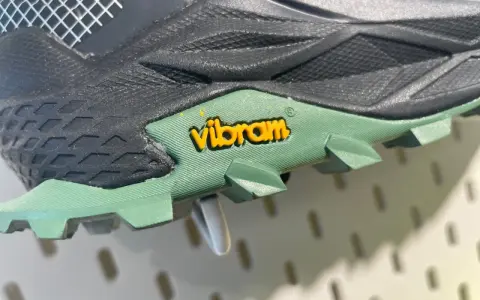 Detailaufnahme einer grünen Vibram Sohle mit gelbem Logo. Mögliche Nachteile: Abnutzung des Profils bei starker Beanspruchung.