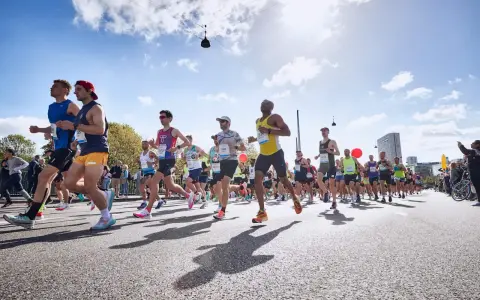 Läufer in einem Marathon, die ihr Lungenvolumen trainieren. Die Sonne scheint, der Himmel ist blau mit Wolken.