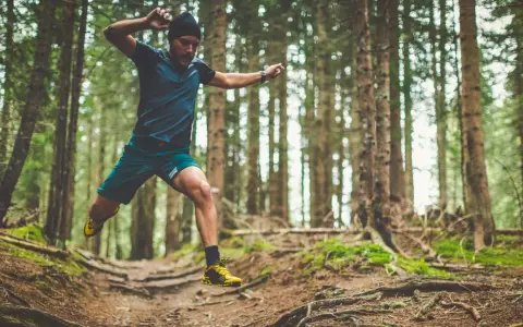 Mann im Sprung beim trailrunning training im Wald.