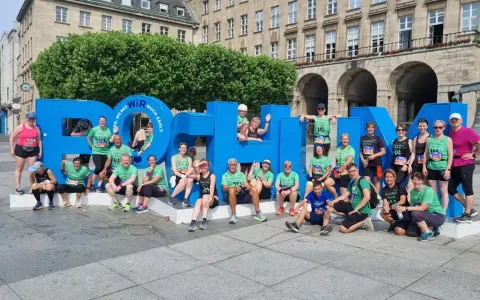 Gruppe feiert Erfolg beim urban run Bochum vor riesiger blauer Schrift.