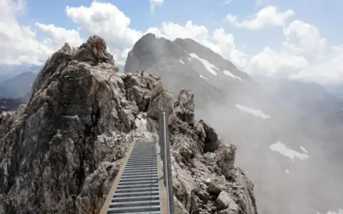 Ein steiler Metallsteg führt über felsige Gipfel. Ein Abenteuer auf dem Heilbronner Weg wandern.