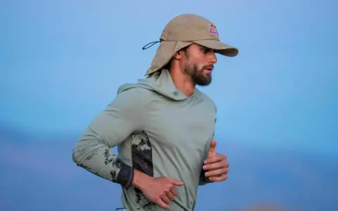Läufer mit Bart und Sonnenschutz-Cap von Red Bull im Laufschritt, auf dem Weg zum Ultramarathon Weltrekord.